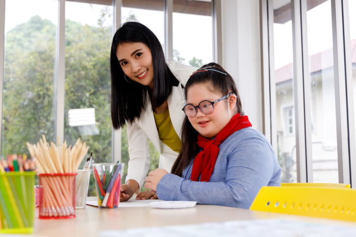 An educational Assistant assisting a student with special learning needs during classroom activities, reflecting the educational assistant skills employers want
